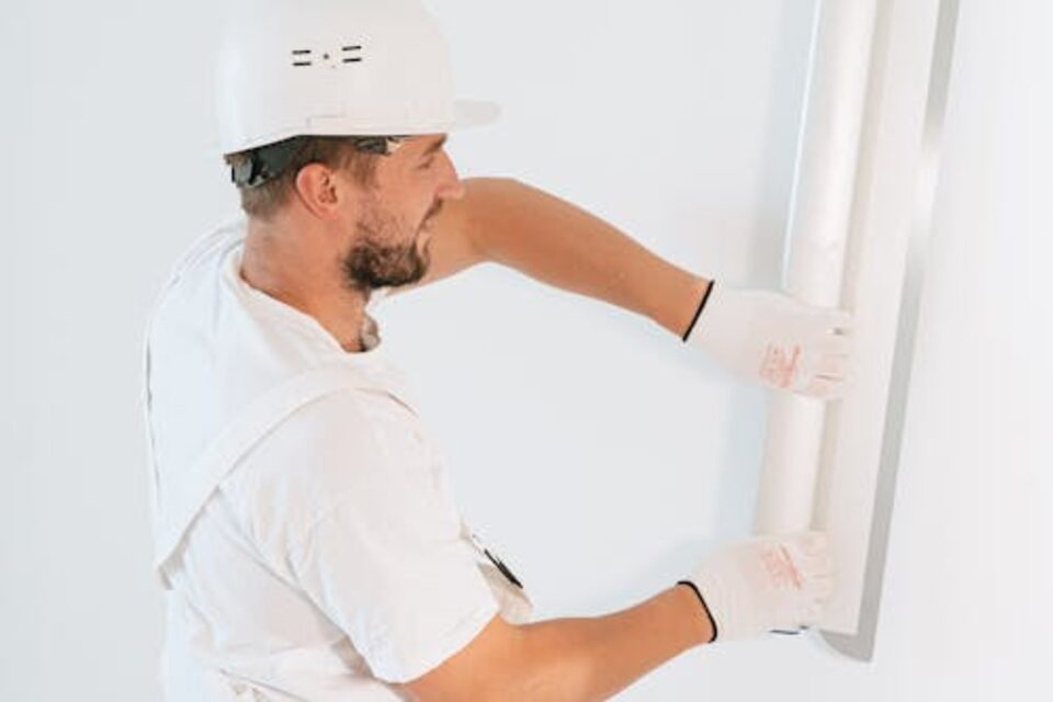 Technician patching and smoothing drywall around a window